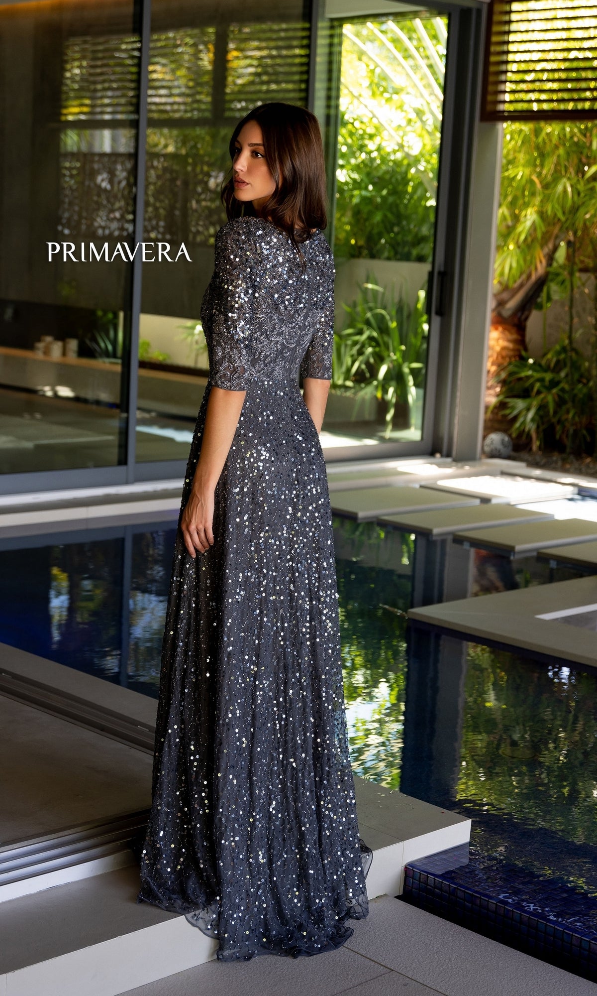 A woman in the Long Prom Dress 13115 by Primavera, featuring a scoop neck, A-line silhouette, beaded details, and short sleeves.